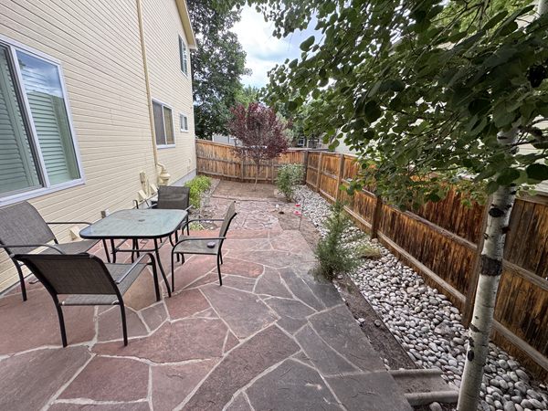 After: cleared flagstone patio with a rock border along the fence